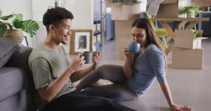 Happy biracial couple moving house, holding key and drinking coffee