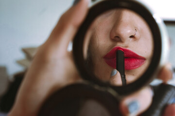 Mujer pintando sus labios de rojo frente al espejo