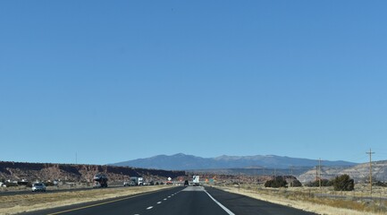 McCartys, New Mexico, USA - November 21, 2021: Mountains in the Distance as a Desert Highway Passes Through a Red Rock Valley on a Clear Fall Day