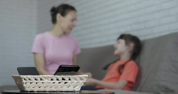 Put telephone on table. A moderm mother with her child put phones on the table and speak in the bed.