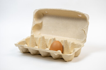 The last chicken brown egg in a carton on a white background. Natural product. No waste. Cardboard...