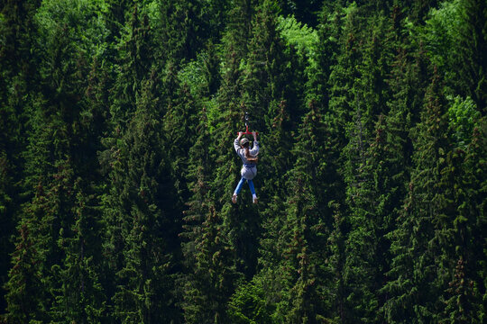 A girl of unrecognizable appearance descends a tightrope on a zipline at high altitude