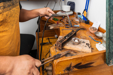 Man using a blowtorch to make a piece of jewellery in a craft workshop