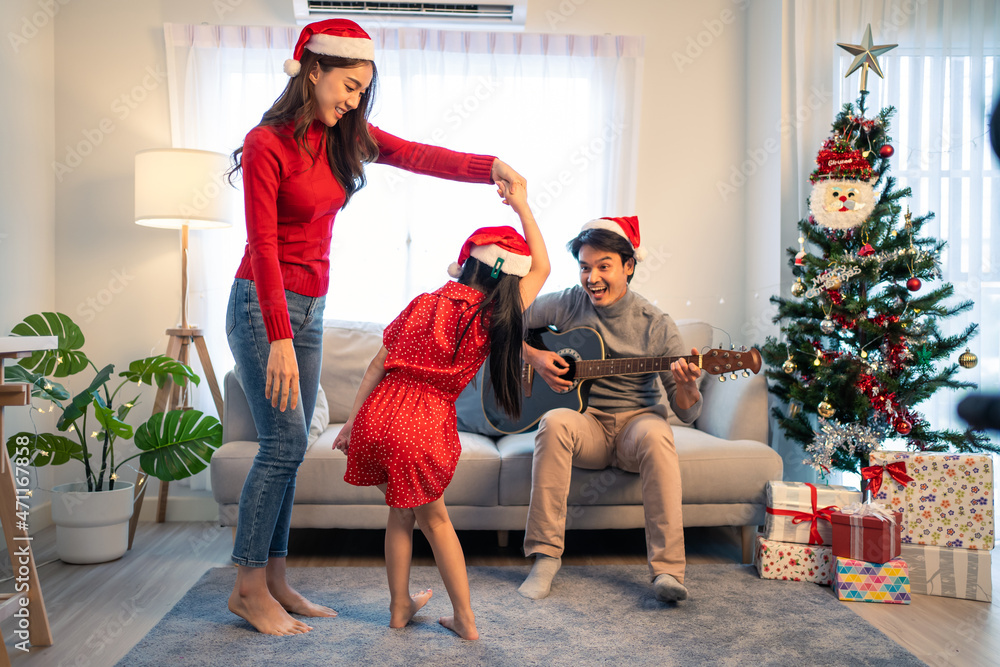 Wall mural asian lovely family member enjoy sing christmas song together at home.