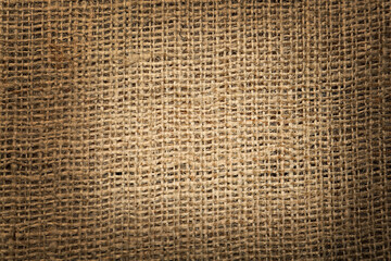 Texture of natural burlap fabric as background, top view. Vignette effect