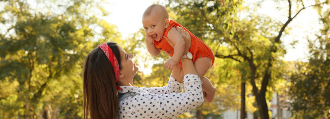 Happy mother with adorable baby in park on sunny day. Banner design