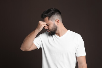 Young man suffering from headache on dark background