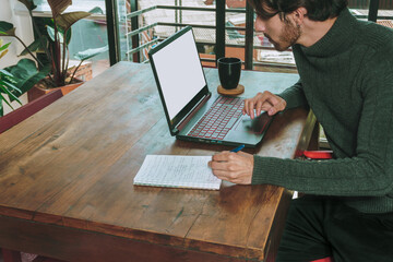 Hombre en frente de computador portatil trabajando en negocios y videollamada