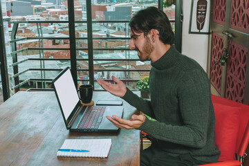 Hombre en frente de computador portatil trabajando en negocios y videollamada