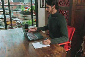 Hombre en frente de computador portatil trabajando en negocios y videollamada