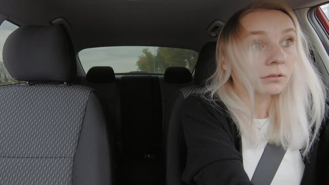 A girl is driving a car, brakes sharply at a pedestrian crossing and swears loudly. People are driving in a car