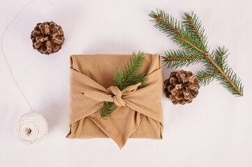 Wrapping Christmas and Holiday present with a brown zero waste Furoshiki wrap nest to winter and festive decor. 