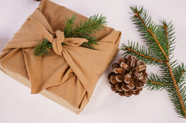 Wrapping Christmas and Holiday present with a brown zero waste Furoshiki wrap nest to winter and festive decor. 