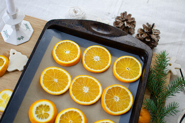 Oranges on a baking tray getting ready to be transformed into homemade Christmas ornaments