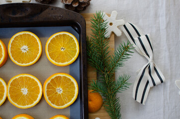 Oranges on a baking tray getting ready to be transformed into homemade Christmas ornaments