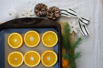 Obraz na płótnie Canvas Oranges on a baking tray getting ready to be transformed into homemade Christmas ornaments
