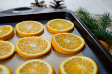 Oranges on a baking tray getting ready to be transformed into homemade Christmas ornaments