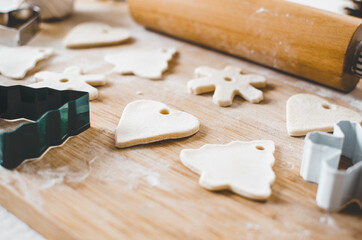 White, salt dough, homemade Christmas tree ornaments in the shape of trees, hearts and snowflakes.