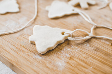 Fototapeta na wymiar White, salt dough, homemade Christmas tree ornaments in the shape of trees, hearts and snowflakes.