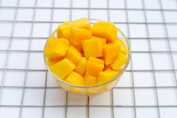 Tropical fruit, Mango cube slices in glass bowl on white background.