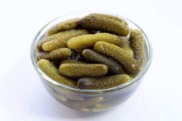 Pickled gherkins or cucumbers in glass bowl on white background.