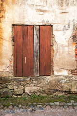 Old Brick Wall Texture. Painted Distressed Wall Surface. Grunge Red Stonewall Background. Shabby Building Facade With Damaged Plaster. Window, beaten with boards