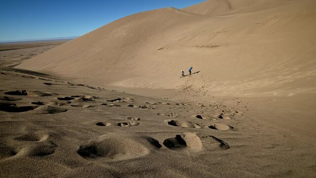 Sand boarding down a slope at Great Sand Dunes National Park, Colorado, USA