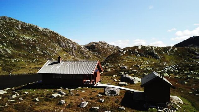 Amazing panning shot of a lonely norwegian cabin surrounded by green hills , 4k aerial
