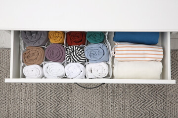 Open drawer with folded clothes indoors, top view. Vertical storage