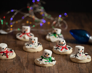 Fototapeta na wymiar Christmas sugar cookies designed to look like melted snowman with blurred Christmas lights in the background.