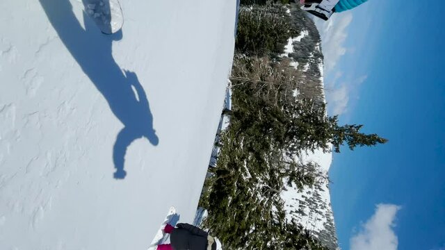 VERTICAL, SELFIE: Young Caucasian man and woman splitboard in the picturesque Slovenian backcountry on a sunny day. Tourist couple shreds fresh powder snow during a split boarding trip in Slovenia.