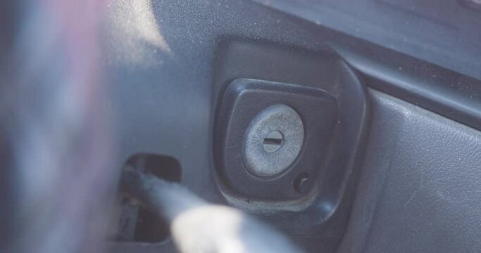A key is inserted into the ignition and turned to start the vehicle. Shot in slow motion.