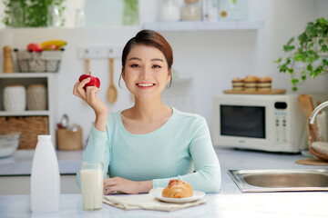Young attractive woman with milk and healthy breakfast in kitchen