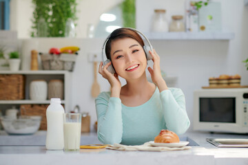 Obraz na płótnie Canvas Young beautiful woman using enjoying music while healthy breakfast