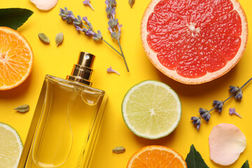 Flat lay composition with bottle of perfume and fresh citrus fruits on yellow background