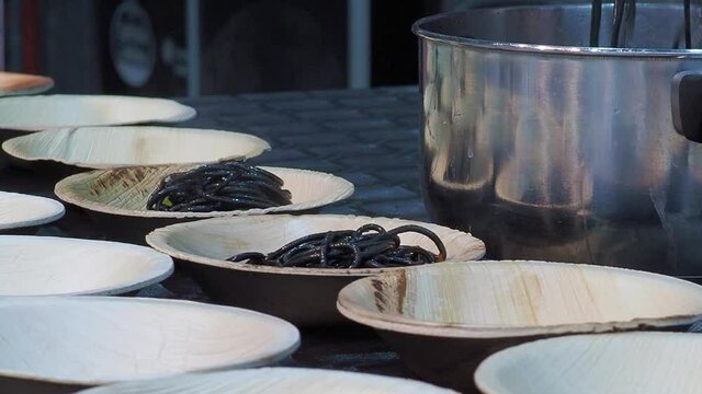 cook plates in bowls for tasting of spaghetti with squid ink
