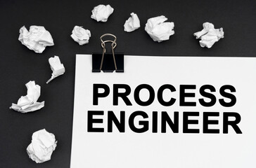 On a black background, there are crumpled pieces of paper and paper with the inscription - Process Engineer