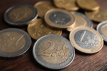 Many Euro coins on wooden table, closeup