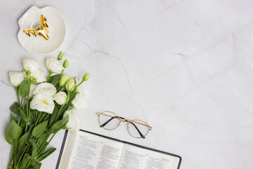 Bible with white roses and glasses over the light marble background. 