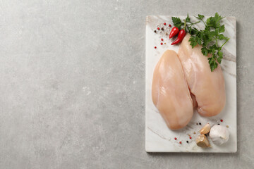 Raw chicken breasts and ingredients on light grey table, top view. Space for text