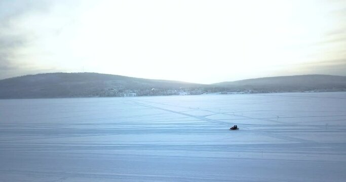 Person Riding Snow Mobile On Snowy Field With Mountain Views In Kiruna, Sweden. - aerial