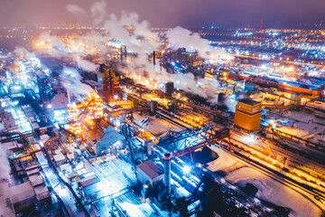 Aerial view of steel plant at night with smokestacks and fire blazing out of the pipe. Industrial...