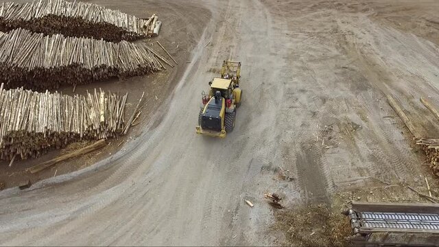 Overhead drone view of machines adding logs into an industrial wood chipper creating wood chips for pulp and then paper.