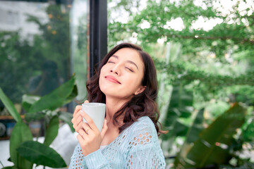 Portrait of happy young woman with cup of hot beverage