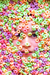 Fototapeta na wymiar Rostro con expresiones de mujer joven sumergida en cereal de colores