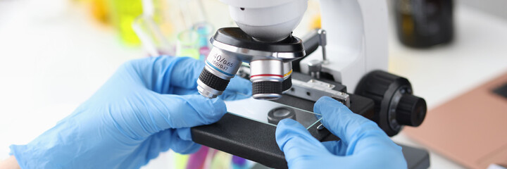 Scientist in gloves holds glass from microscope