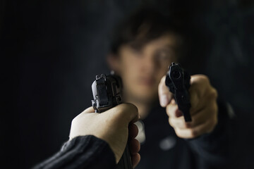 Threat to life. Close-up of hand with weapon. Two men point pistols at each other. Shootout of criminals with revolvers. Dark background and dangerous situation. Killer or murderer.