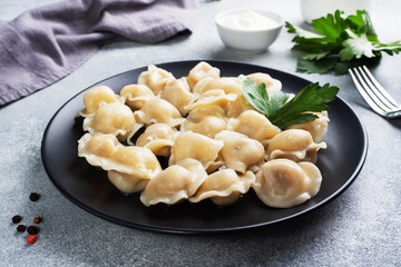 Traditional pelmeni, ravioli, dumplings filled with meat on plate, russian kitchen. Light concrete background, copy space.