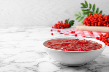 Delicious rowan jam in bowl and berries on white marble table. Space for text - obrazy, fototapety, plakaty