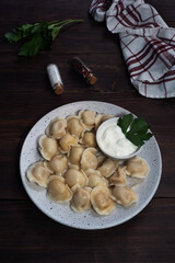 Traditional pelmeni, ravioli, dumplings filled with meat on plate, russian kitchen. Wooden rustic background, copy space.